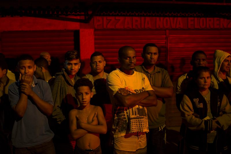“Residents watch as police work the crime scene where a man was murdered in Mage, greater Rio de Janeiro, Brazil.”